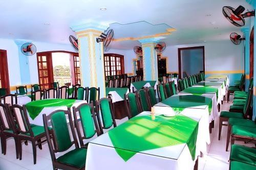 a dining room with green and white tables and chairs at Khách Sạn Cây Thông in Tam Ðảo