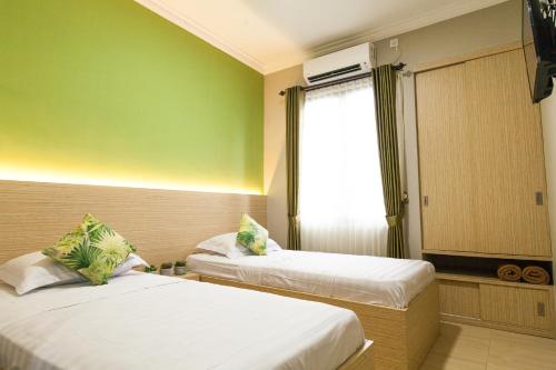 two beds in a room with green walls and a window at Azzahra Guest House Syariah near Juanda in Sidoarjo
