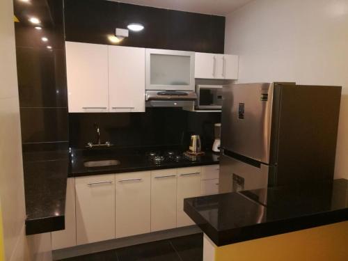 cocina con armarios blancos y nevera de acero inoxidable en Apartamento Miraflores Boulevard Tarata, en Lima