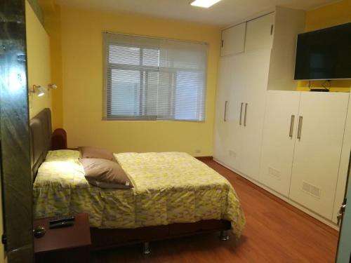 1 dormitorio con 1 cama, ventana y TV en Apartamento Miraflores Boulevard Tarata, en Lima