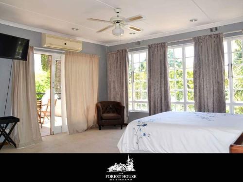 a bedroom with a bed and a chair and windows at Forest House B&B in Harding