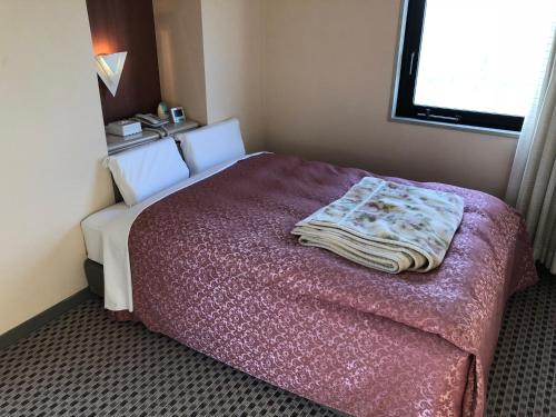 a bedroom with a bed with a blanket on it at Hotel Hikari Hills in Shunan