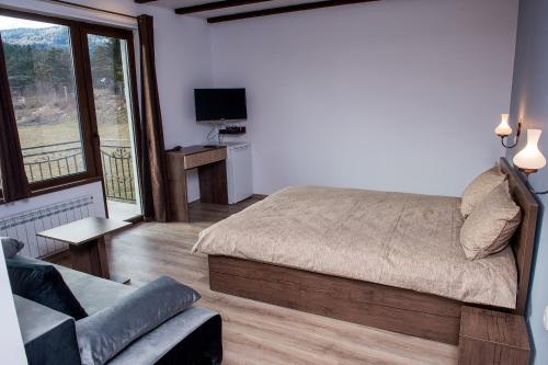 a bedroom with a bed and a couch and a television at Vila Lidia in Tsigov Chark