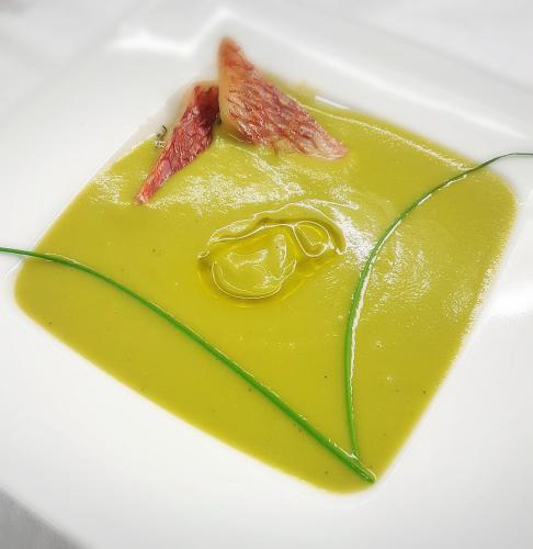 a plate with a yellow sauce and a piece of food at Hotel Antines in La Villa