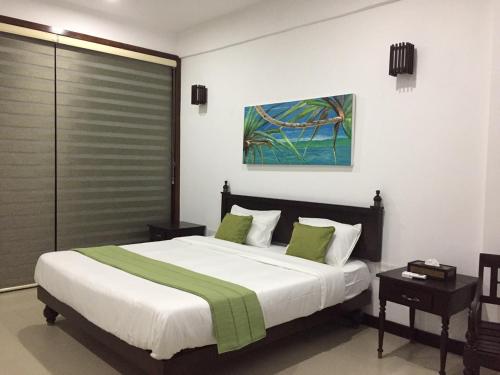 a bedroom with a large bed with green pillows at The Pleasure Kosgoda in Bentota