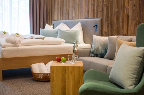 a hotel room with a bed and a couch and a table at Hotel Der Waldhof in Zell am See
