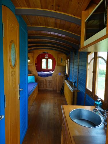 a kitchen with a sink and a room with a bed at Une roulotte et des chevaux in Treffléan