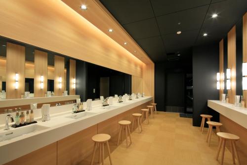 a bathroom with a row of sinks and stools at THE SINGULARI HOTEL & SKYSPA at UNIVERSAL STUDIOS JAPAN in Osaka