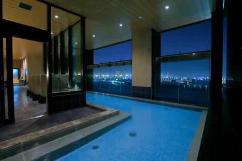 a swimming pool in a building with a view of the city at THE SINGULARI HOTEL & SKYSPA at UNIVERSAL STUDIOS JAPAN in Osaka