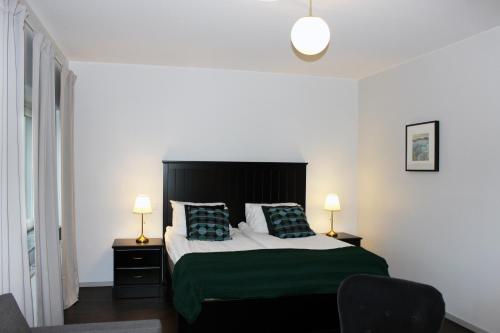 a bedroom with a bed with a green blanket and two lamps at Rasta Värnamo in Värnamo