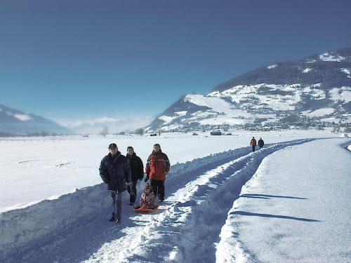 a group of people walking on a snow covered road at Pension Lacknerhof in Piesendorf