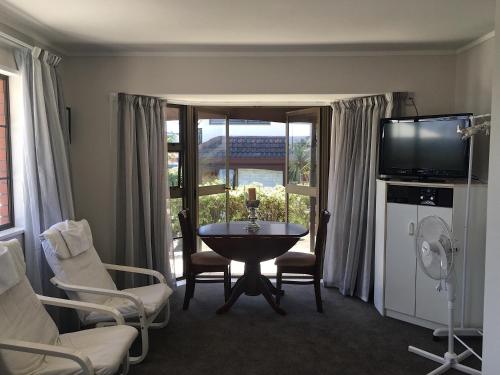 een woonkamer met een tafel en stoelen en een televisie bij Victoria Road B&B in Mount Maunganui