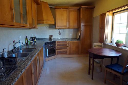 a kitchen with wooden cabinets and a sink and a table at Coworksurf - Villa dos Irmãos in Ericeira