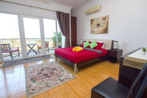 a bedroom with a red bed and a balcony at Lana Villa in Muscat