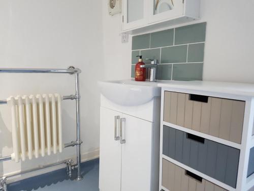 a white bathroom with a sink and a sink at Kingfisher cottage in Worthing