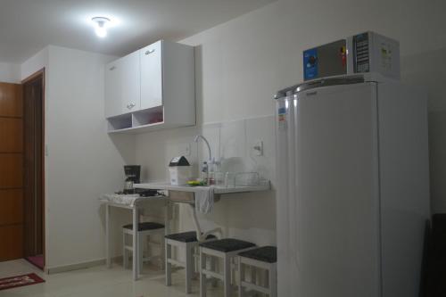 a kitchen with a refrigerator and a counter with stools at Loft Centro in Arraial do Cabo