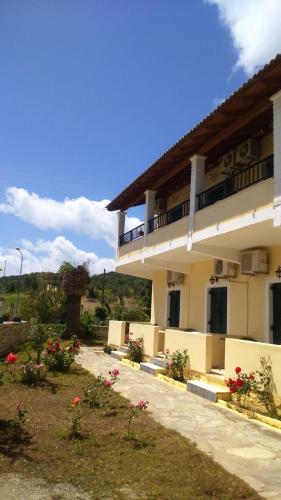 een gebouw met een balkon en een tuin met bloemen bij Rose Garden Rooms in Moraitika