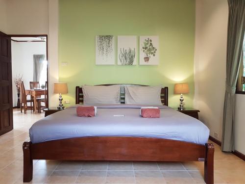 a bedroom with a large bed with two pink pillows at Woodlawn Villas Resort in Koh Tao