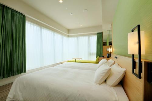 a bedroom with a large white bed with a large window at THE SINGULARI HOTEL & SKYSPA at UNIVERSAL STUDIOS JAPAN in Osaka