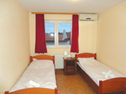 Habitación pequeña con 2 camas y ventana en Prenoćište "Magnus" en Slavonski Brod