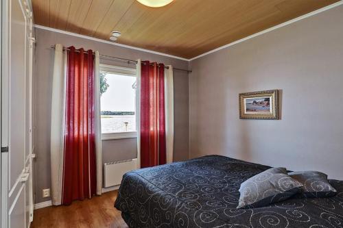 Schlafzimmer mit roten Vorhängen, einem Bett und einem Fenster in der Unterkunft Villa SUNSET in Malax