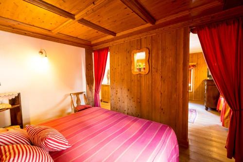 a bedroom with a bed in a room with wooden walls at Hotel Lyshaus in Gressoney-Saint-Jean