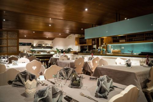 ein Restaurant mit weißen Tischen und Stühlen sowie einer Küche in der Unterkunft Hotel Bristol in Saas-Fee