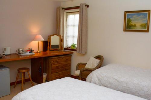 a bedroom with a bed and a desk with a mirror at Clarke Cottage Guest House in Dunfermline