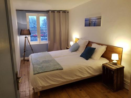 une chambre avec un grand lit blanc avec une fenêtre dans l'établissement Le Charlot, à Saint-Valery-sur-Somme