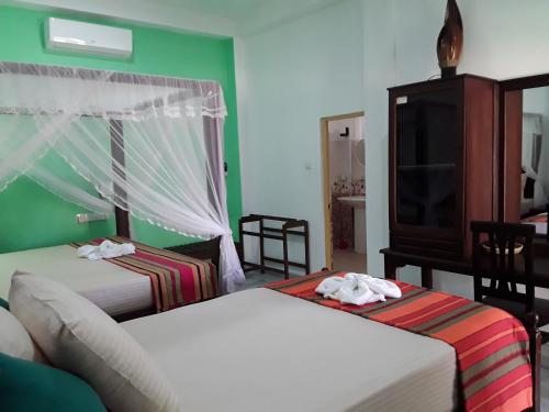 two beds in a room with green walls at Akurala Beach Park in Hikkaduwa