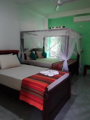 two beds in a room with green walls at Akurala Beach Park in Hikkaduwa