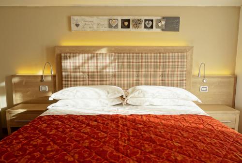 a bedroom with a red bed with two pillows at Hotel Alpina in Pinzolo