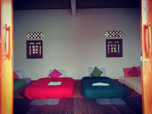 two beds in a room with red and blue at Black Lava Hostel and Lodge in Kintamani