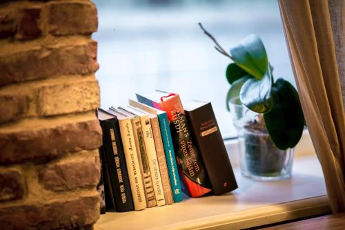 a row of books on a shelf next to a brick wall at Hotel Benevilla in Alūksne