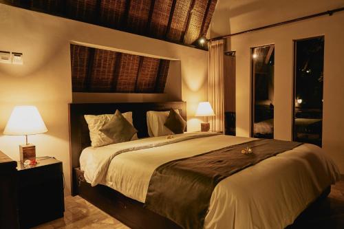 a bedroom with a large bed and two lamps at The Garden Villa in Sanur