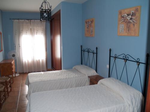 um quarto com 2 camas e uma parede azul em Casa Rural El Botánico em Casatejada