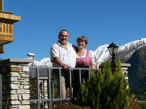 a man and woman standing on a balcony with a mountain at Hotel Kranebitt in Val di Vizze