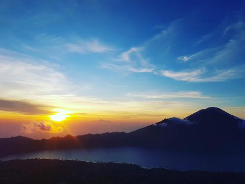 a view of the sun setting over a mountain range at Black Lava Hostel and Lodge in Kintamani