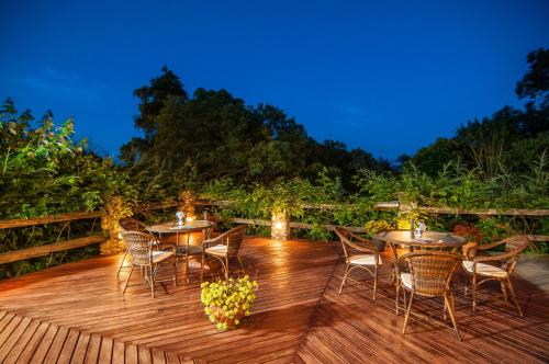 a wooden deck with tables and chairs at night at Pousada Cantinho das Estrelas in Monte Verde
