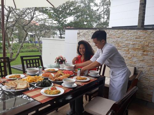 a man and woman standing at a table with food at Emblem Sea 3 bedroom villas in Da Nang