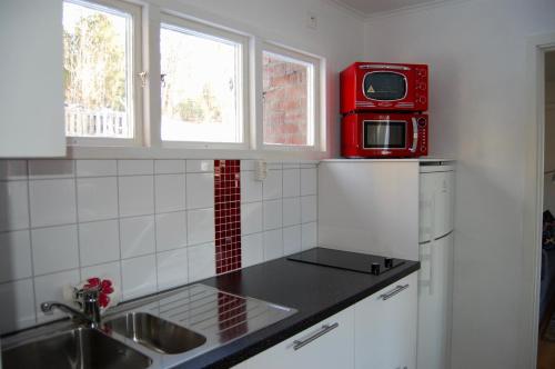 La cocina está equipada con fregadero, microondas y nevera. en Lilla Solhaga, en Ljungskile