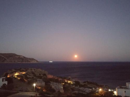 a full moon rising over the ocean at night at Olympos Studios in Amoopi