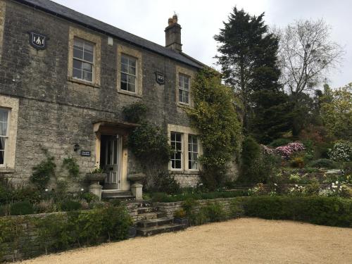 an old stone house with a garden in front of it at Roundhill Farmhouse in Bath