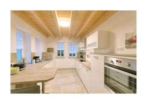 a white kitchen with a table and a wooden ceiling at Pröser Mühle in Weilmünster