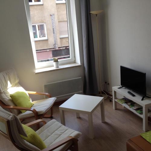 a living room with a tv and a chair and a table at Le Châtaignier in Forbach