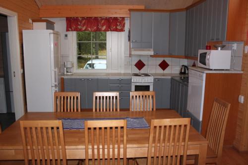 una cucina con tavolo in legno, sedie e forno a microonde di Kuusitorppa a Varpaisjärvi