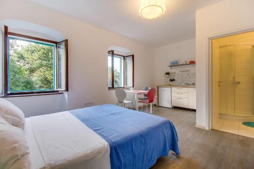a bedroom with a bed and a table and a kitchen at BigBlue house in Veli Lošinj
