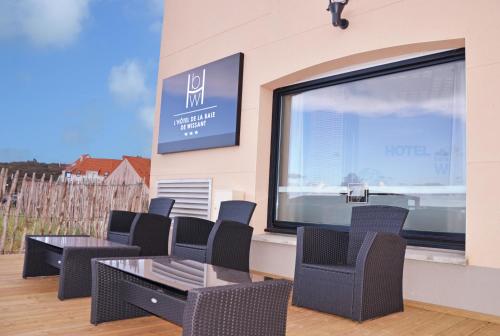 a patio with chairs and tables and a large window at Logis- Hôtel de la Baie de Wissant & Appartements in Wissant