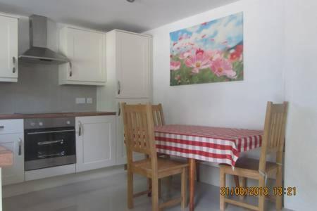 a kitchen with a table and two chairs and a table and a kitchen with white at Littlebridge Farmhouse in Bude