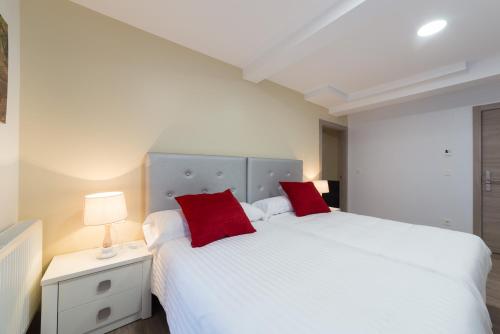 a bedroom with two white beds with red pillows at Petit Goierri in Ormáiztegui